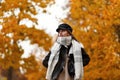 Beautiful stylish cute young woman in a brown trendy jacket in an elegant black hat with a vintage warm scarf walks in the autumn Royalty Free Stock Photo