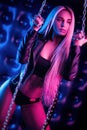 Beautiful stylish fashionable girl in bodysuit posing in photo Studio on dark background with chains in neon light Royalty Free Stock Photo