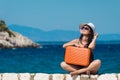 Female sitting on seaside wall and holding suitcase against the blue sea Royalty Free Stock Photo