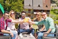 Beautiful stylish friends are using a digital tablet, drinking coffee and smiling while resting in the park Royalty Free Stock Photo