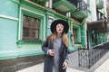 Beautiful stylish girl in a coat and hat poses against the background of the architecture of the old town. Royalty Free Stock Photo