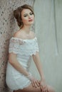 Beautiful stylish girl posing in short white dress against stone wall background. Royalty Free Stock Photo