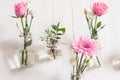 Beautiful stylish holiday decoration. Roses and gerbera in jars are suspended from white wall, front view