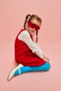 Beautiful, stylish, little girl, child in red dress, blue tights and red glasses posing over pink studio background Royalty Free Stock Photo