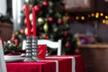 Beautiful and stylish table setting with Christmas decorations in living room, red candles and blurred background with fir tree Royalty Free Stock Photo