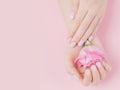 Beautiful stylish trendy female pink manicure with flower on background, top view. Concept beauty