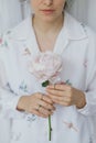 Beautiful stylish woman holding pink peony. Young female in boho floral shirt with flower in hands