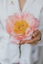 Beautiful stylish woman holding pink peony. Young female in boho floral shirt with flower in hands