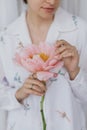 Beautiful stylish woman holding pink peony. Young female in boho floral shirt with flower in hands