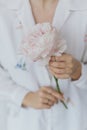 Beautiful stylish woman holding pink peony. Young female in boho floral shirt with flower in hands