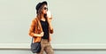 Beautiful stylish woman model wearing black round hat, brown jacket and handbag on gray background Royalty Free Stock Photo