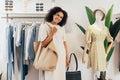 Beautiful stylish woman with shopping bag standing in boutique at a rack and looking at camera Royalty Free Stock Photo