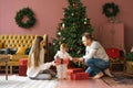 Beautiful stylish young family sitting on the floor near the Christmas tree. Family members exchange gifts Royalty Free Stock Photo