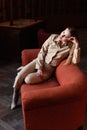 Beautiful stylish young lady in suit sitting on the red sofa Royalty Free Stock Photo