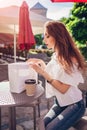 Beautiful stylish young woman with shopping bags chilling in outdoor cafe on city street and checking her purchases. Royalty Free Stock Photo