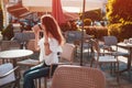 Beautiful stylish young woman with shopping bags chilling in outdoor cafe on city street and talking on phone. Royalty Free Stock Photo