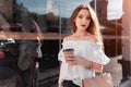 Beautiful stylish young woman with shopping bags chilling on city street and drinking coffee. Summer fashion Royalty Free Stock Photo