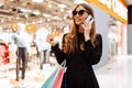 Beautiful stylish young woman, with shopping bags, talking on a mobile phone in a shopping center Royalty Free Stock Photo