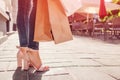 Beautiful stylish young woman with shopping bags walking on city street in summer. Closeup of shoes and purchases Royalty Free Stock Photo