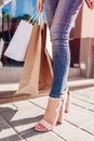 Beautiful stylish young woman with shopping bags walking on city street in summer. Closeup of shoes and purchases. Sale Royalty Free Stock Photo