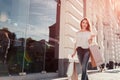 Beautiful stylish young woman with shopping bags walking on city street in summer. Happy girl holding purchases Royalty Free Stock Photo