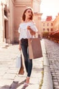 Beautiful stylish young woman with shopping bags walking on city street in summer. Sale Royalty Free Stock Photo