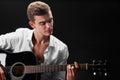 A beautiful and success man playing guitar and singing songs on a black background. Music, songs, rock, pop concept. Royalty Free Stock Photo