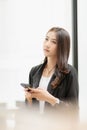 Beautiful successful asian businesswoman holding mobile phone using smartphone in office Royalty Free Stock Photo