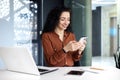 Beautiful and successful business woman with curly hair at workplace inside office using phone, latin american boss Royalty Free Stock Photo