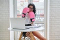 Businesswoman sitting at desk with laptop computer in office wearing boxing gloves Royalty Free Stock Photo