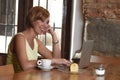 Beautiful successful woman working at coffee shop with laptop computer enjoying coffee cup Royalty Free Stock Photo