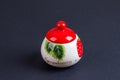 A beautiful sugar bowl with painted strawberries and a red lid, filled with white sugar on a black background