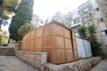 A beautiful sukkah made of wood inside the courtyard of a building, surrounded by trees and plants,