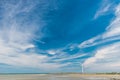 Beautiful summer clouds over a beach with wind turbines in the horizon Royalty Free Stock Photo