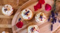 Beautiful summer cupcakes flat lay of floral cupcakes on wood tray with lavender flowers and red rose petals Royalty Free Stock Photo