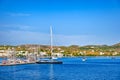 Beautiful summer day, sunshine in typical marina of Greek island. Sailboats and yachts at jetty. Whitewashed houses on