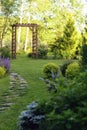 Beautiful summer garden view with curvy stone pathway and wooden archway. Royalty Free Stock Photo