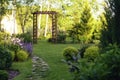 Beautiful summer garden view with curvy stone pathway and wooden archway. Royalty Free Stock Photo