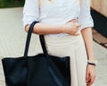 Beautiful summer Girl posing on the street with a black red super fashionable handbag in a White blouse and skirt on a