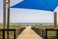 A beautiful summer landscape at the beach with a wooden footpath, people relaxing on the beach with colorful umbrellas, blue ocean