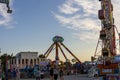 A beautiful summer landscape at the Carolina Beach Boardwalk with people, carnival rides, lush green palm trees