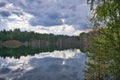 Beautiful summer landscape, forest trees are reflected in calm river water against a background of blue sky and white clouds Royalty Free Stock Photo