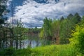 Beautiful summer landscape, forest trees are reflected in calm river water against a background of blue sky and white clouds Royalty Free Stock Photo