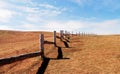 Landscape of pasture for cattle, wooden fence in prairie, blue sky with clouds. Royalty Free Stock Photo