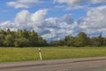 Beautiful summer landscape view. High-voltage electric power transmission line between green trees on blue sky with white clouds Royalty Free Stock Photo