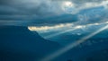 Beautiful summer mountain landscape. Dark clouds over a mountain ravine, oblique rays of evening sun breaking through Royalty Free Stock Photo