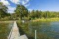 Beautiful summer natural landscape view. View from wooden bridge on lake coast line with boats and green forest trees Royalty Free Stock Photo