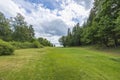 Beautiful summer nature landscape view. Greengrass field on front and Baltic sea on cloudy sky background