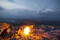 Beautiful summer night in mountain. Bright fire burns on rocky mountain top under blue cloudy sky Royalty Free Stock Photo