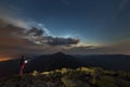 Beautiful summer night in mountains. Profile silhouette of young tourist hiker man with flashlight standing alone on rocky mountai Royalty Free Stock Photo